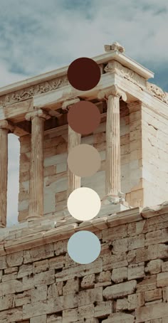 an old building with columns and circles hanging from it's roof, against a cloudy sky