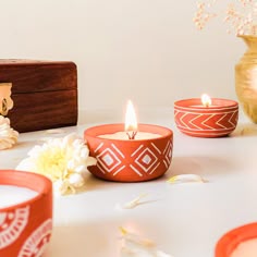 three tea lights sitting on top of a table next to flowers and a wooden box