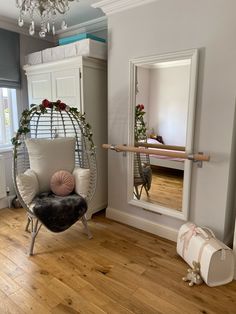 a chair and mirror in a room with wooden floors, white walls and wood flooring