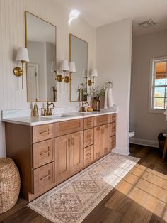 a bathroom with two sinks, mirrors and rugs on the floor in front of it