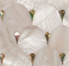 several white shells are arranged together on a surface with gold and green accents in the center