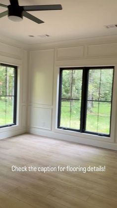 an empty room with two large windows and a ceiling fan in the middle of it