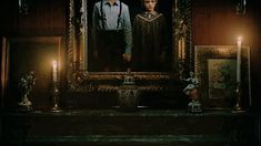 two people standing in front of a painting with candles