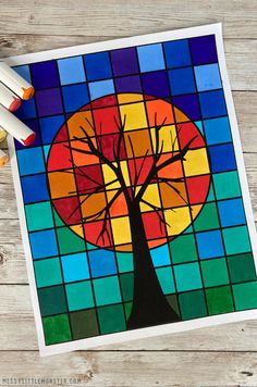 an art project with stained glass and colored crayons on the table, featuring a tree