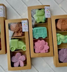 four different shaped soaps in boxes on the floor next to each other with flowers and animals