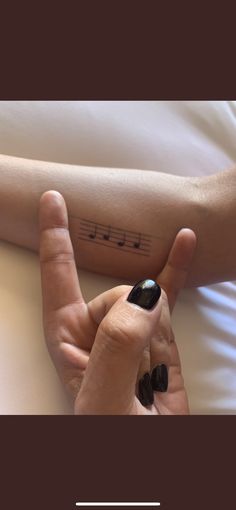 a woman's arm with music notes on it and her hand in the air