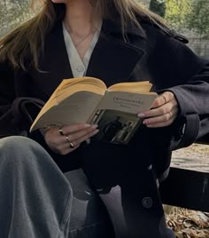 a woman sitting on a bench reading a book