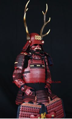 a man in armor with horns and antlers on his head, standing next to two suitcases