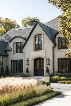 a large white house with lots of windows and black shutters on the front door