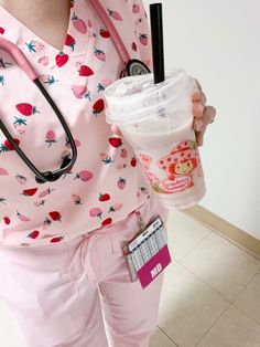 a woman in pink scrubs holding a cup of coffee