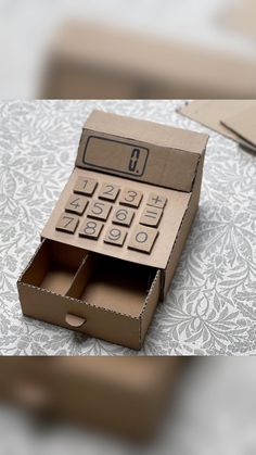 an open cardboard box with a calculator in it sitting on top of a table