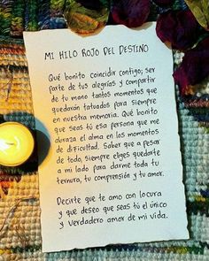 a paper with writing on it next to a lit candle