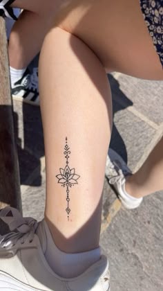a woman's leg with a tattoo on it and a small flower in the middle
