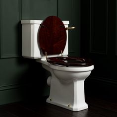 a white toilet sitting in a bathroom next to a green wall and wooden flooring