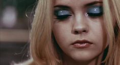 a woman with long blonde hair wearing blue eyeshadow and black eyeliners