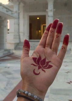 a woman's hand with red paint on it and a flower painted on the palm