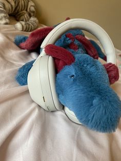 a stuffed animal laying on top of a bed with headphones around it's ears