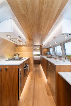 a galley kitchen with wood paneling and white counter tops on both sides, along with stainless steel appliances