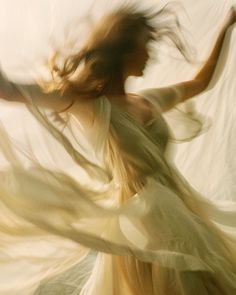 a woman in a white dress is dancing with her arms spread out to the side