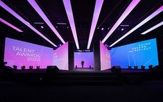 the stage is lit up with purple and blue lights for an award ceremony or conference