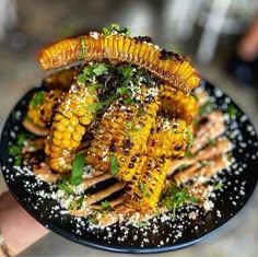 a black plate topped with grilled corn and garnish
