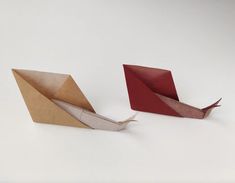 two origami boats are sitting side by side on a white surface and one is folded in half