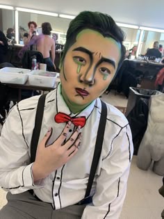 a man in a white shirt and red bow tie with his hands on his chest