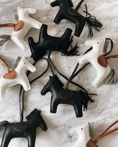 five black and white horse ornaments on a marble table with brown leather cord holders in the shape of horses