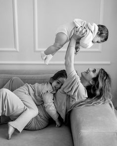 a woman laying on top of a couch holding a baby