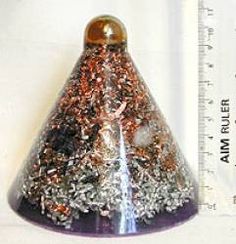 a purple and gold colored glass cone with sprinkles on the top, next to a ruler