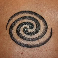 a close up of a person's chest with a tattoo on it that looks like a spiral