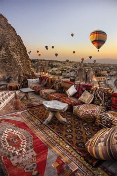 an outdoor area with lots of colorful rugs and hot air balloons in the sky