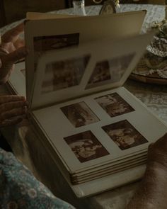 an open book sitting on top of a table next to a person's hand