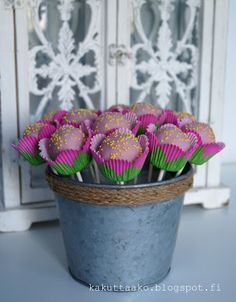 cupcakes in pink and green wrappers sitting on top of a metal bucket