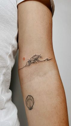 a woman's arm with a small wave tattoo on the back of her left arm