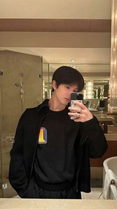 a man taking a selfie in front of a bathroom mirror with his cell phone