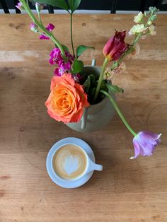 a cup of coffee and some flowers on a table