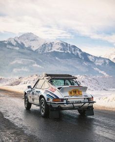 a car driving down a snowy road with mountains in the backgroud and snow on the ground
