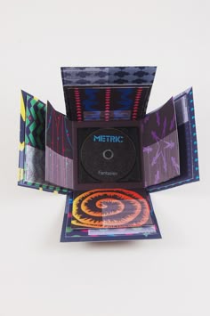 the cd case is open and has colorful designs on it's sides, as well as an abstract design