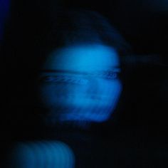 a blurry image of a person's face in the dark with blue light