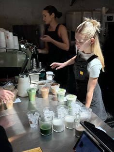 a woman standing in front of a counter filled with cups