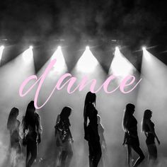 a group of women standing on top of a stage with spotlights in the background