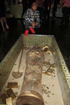 a man sitting in the middle of an open box filled with gold and other items