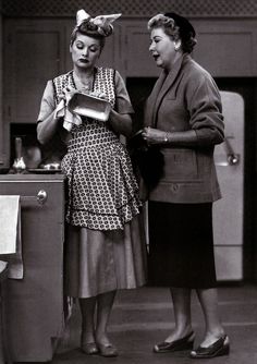 two women standing next to each other in a kitchen