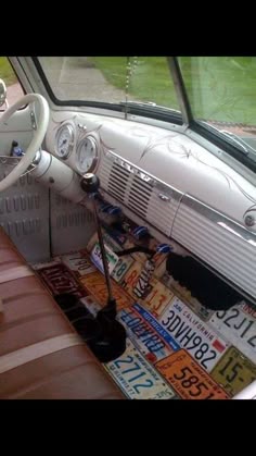 the interior of an old car with license plates on the floor and steering wheel,