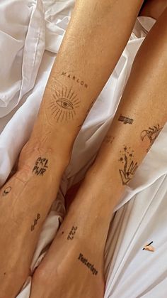 two people with matching tattoos on their legs laying in bed next to each other,
