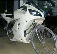 a white motorcycle parked next to a building with an angry face on it's front tire