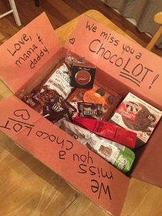 an open box filled with chocolates and candy on top of a wooden floor next to a table