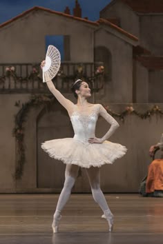 the ballerina is wearing a white tutu and holding a fan in her hand
