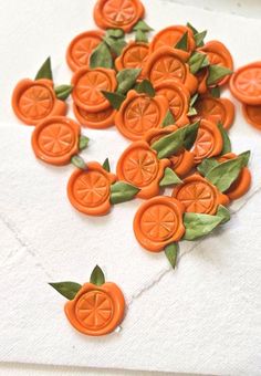 orange buttons with leaves on them sitting on a piece of paper